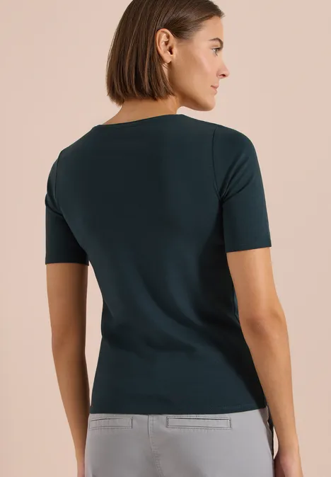 Basic T-Shirt aus Baumwolle deep petrol blue Frau von hinten, trägt ein dunkelgrünes Kurzarmshirt, kinnlanger Bob, neutraler Hintergrund.
