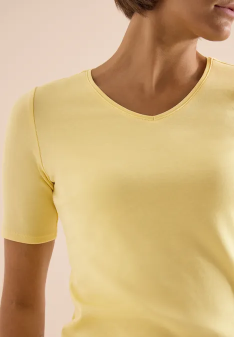Basic katoenen shirt buttermilk yellow Iemand draagt een lichtgeel kort t-shirt met korte mouwen en een ronde hals.