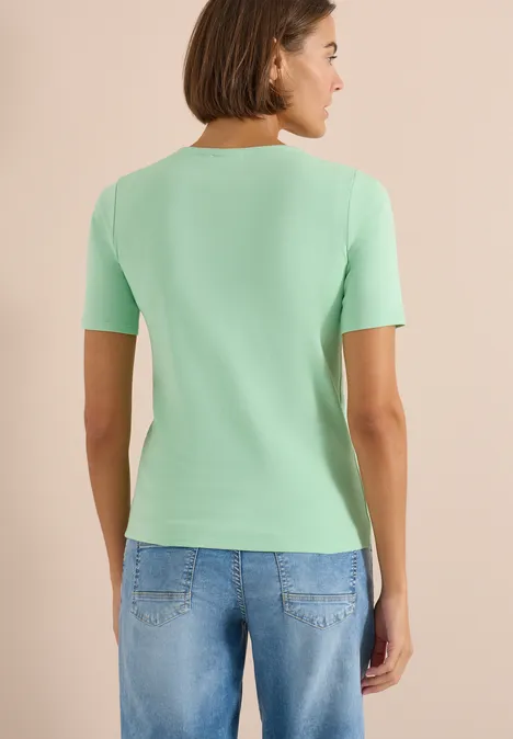 Basic katoenen shirt juicy lime Vrouw van achteren in muntgroen T-shirt en blauwe jeans.