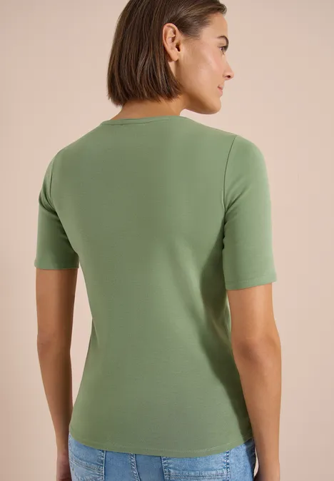 T-shirt basique en coton deep matcha green Femme de dos portant un T-shirt vert à manches courtes et un jean sur fond clair.
