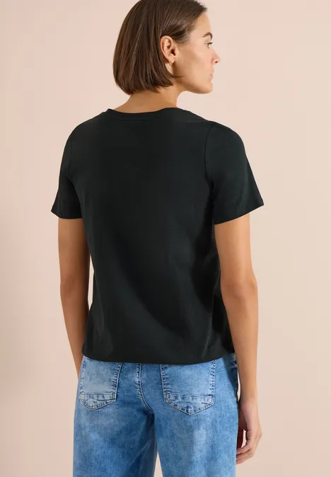 Basic shirt in tuniekstijl palm breeze green Achteraanzicht van een persoon met zwart shirt en blauwe spijkerbroek