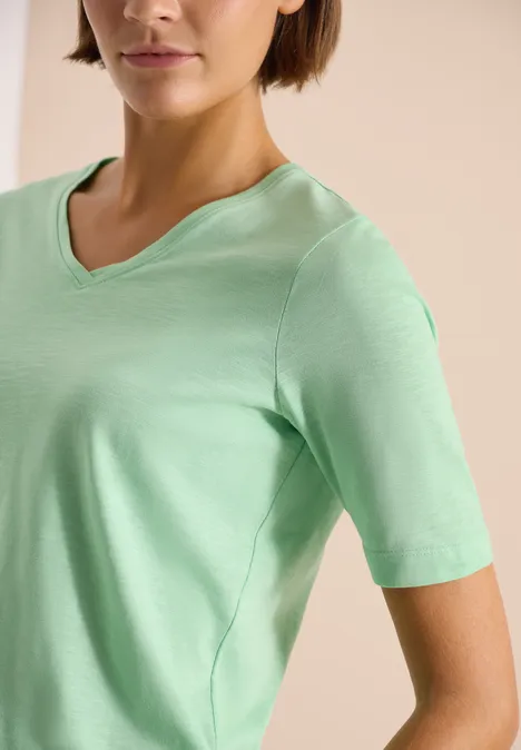 Basic Shirt met V-hals juicy lime Vrouw in mintgroen T-shirt met V-hals tegen een neutrale achtergrond.
