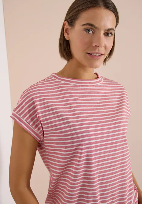 Eine Person trägt ein rosa-weiß gestreiftes T-Shirt vor hellem Hintergrund.