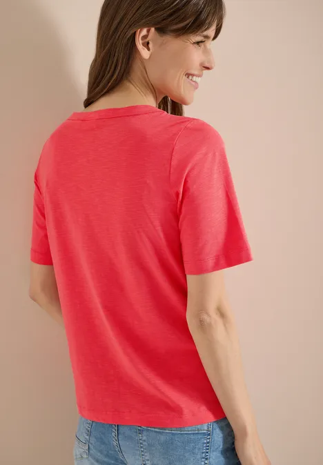 Kurzarm T-Shirt aus reiner Baumwolle coral Rückansicht einer Frau in korallrotem T-Shirt und blauer Jeans vor neutralem Hintergrund.