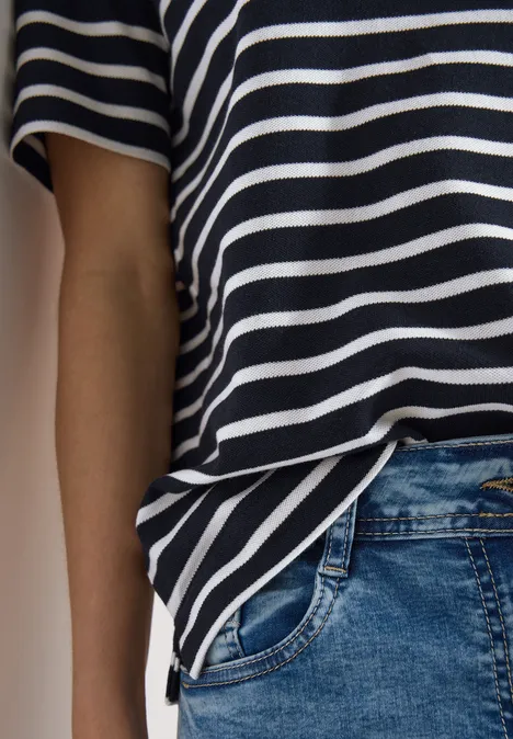 Navy-weiß gestreiftes T-Shirt und blaue Jeans, Seitenansicht eines Oberkörpers.