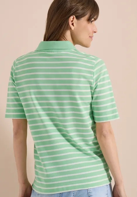 Rückansicht einer Person in einem mintgrün-weiß gestreiften Poloshirt vor beigem Hintergrund.