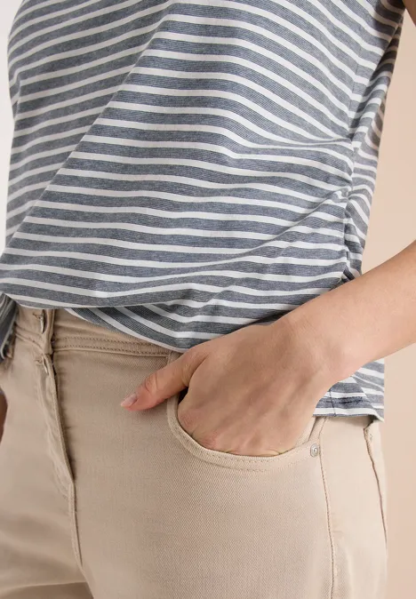 Nahaufnahme eines Oberkörpers mit gestreiftem Shirt und Hand in der Hosentasche.