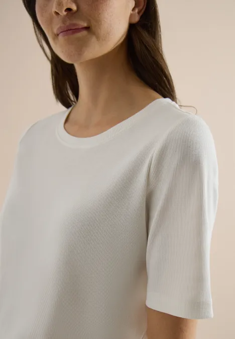 Frau trägt schlichten weißen Rundhals-Shirt mit kurzen Ärmeln.