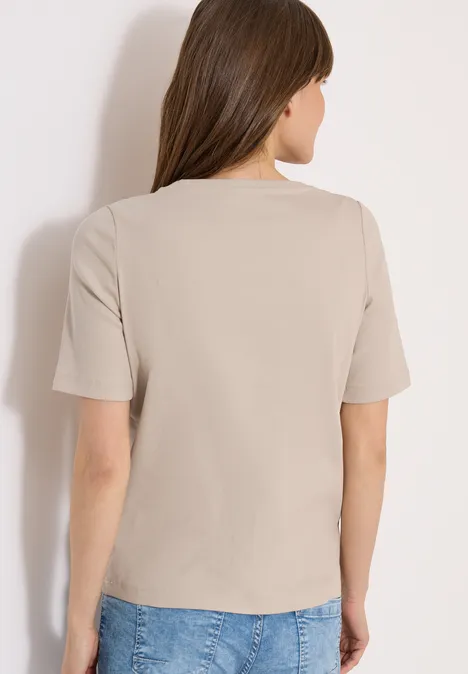 Vrouw van achteren met een beige t-shirt en een blauwe spijkerbroek.