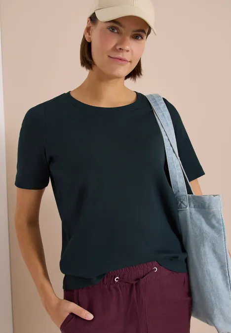 Person trägt schwarzes T-Shirt und lila Hose, mit Stofftasche über der Schulter.