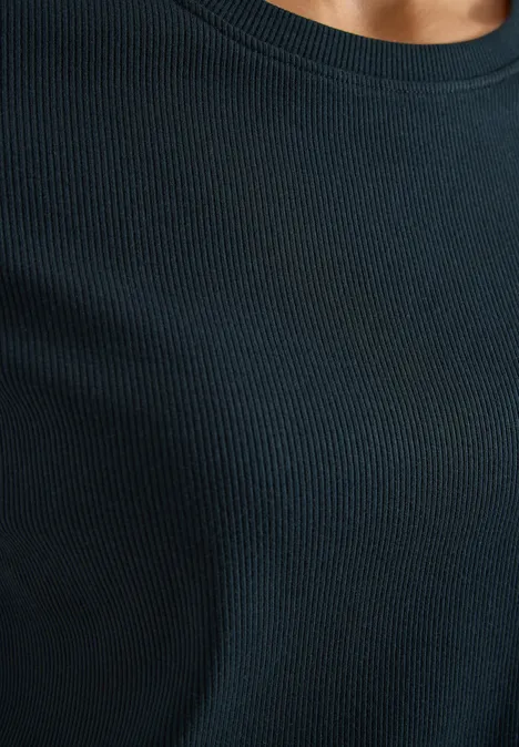 Eine Person trägt ein schwarzes, fein geripptes Oberteil, Blick nur auf den Oberkörper.