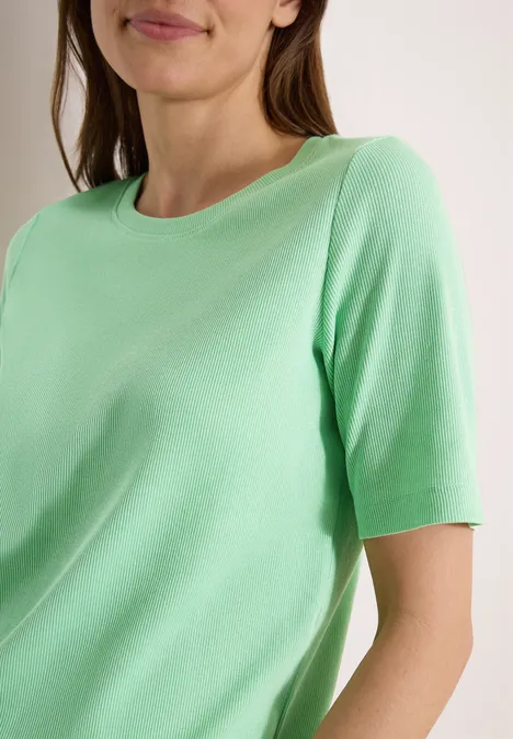 Basic geribd Shirt juicy lime Bovenlichaam van een vrouw in een muntgroen T-shirt, alleen borst en schouders zichtbaar.