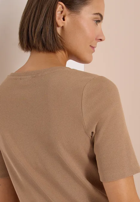 Achteraanzicht van een persoon met kort haar die een beige T-shirt draagt.