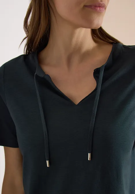 Frau trägt dunkelgrünes T-Shirt mit V-Ausschnitt und Schnürsenkeln