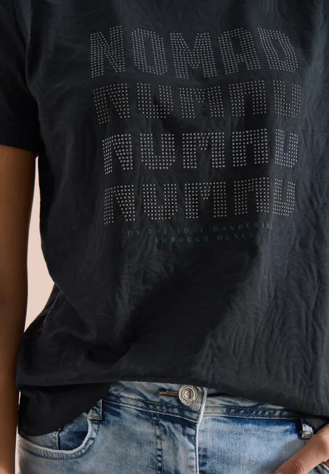 Shirt met korte mouwen in burnout-look palm breeze green Bovenlichaam in spijkerbroek en zwart T-shirt met 'Nomad'-print in stippen.