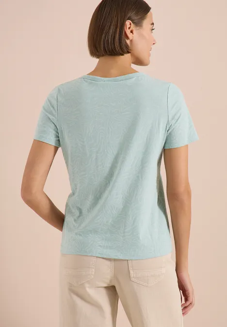 Shirt met korte mouwen in burnout-look crystal mint Achteraanzicht van een vrouw in een lichtblauw T-shirt en beige broek voor een neutrale achtergrond.