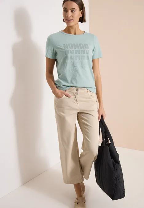 Shirt met korte mouwen in burnout-look crystal mint Vrouw draagt mintgroen T-shirt, wijde beige broek en zwarte shopper voor lichte achtergrond