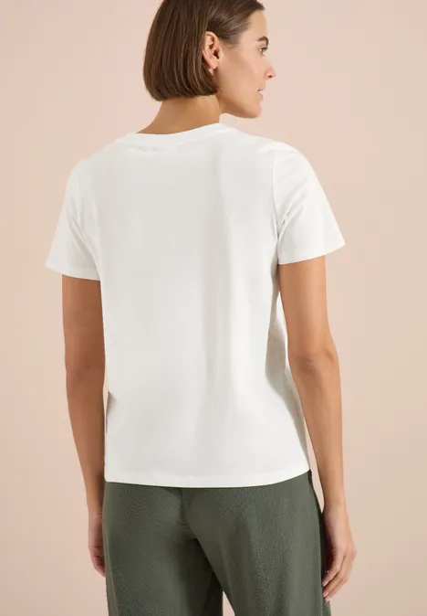 Rückenansicht einer Person in weißem T-Shirt und dunkler Hose vor neutralem Hintergrund.