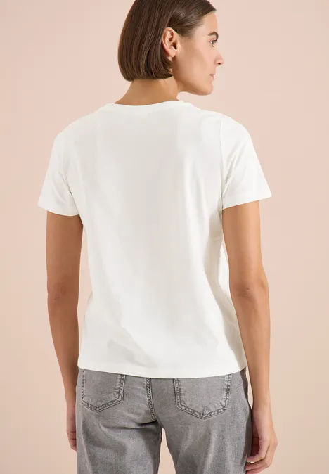T-Shirt mit Rundhals und Frontprint vanilla white Frau steht vor hellem Hintergrund, trägt weißes T-Shirt und graue Jeans, Rückenansicht.