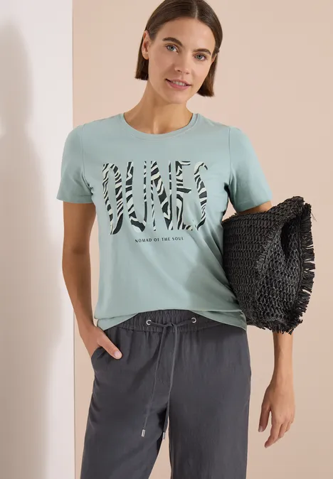 T-Shirt mit Rundhals und Frontprint crystal mint Frau trägt hellblaues T-Shirt mit Zebramuster-Schriftzug, graue Hose und hält eine schwarze, strukturierte Tasche.
