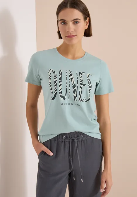 T-Shirt mit Rundhals und Frontprint crystal mint Frau trägt hellblaues T-Shirt mit Zebra-Print-Schriftzug und dunkelgraue, locker sitzende Jogginghose.