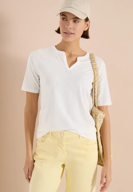 Shirt met gespleten hals in effen kleur vanilla white Persoon met wit t-shirt, gele broek, witte pet en gevlochten schoudertas.