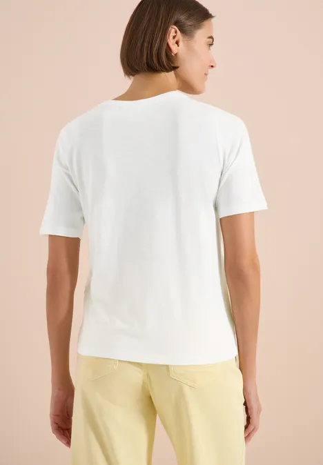Shirt met gespleten hals in effen kleur vanilla white Persoon van achteren met kort bruin haar, in een wit T-shirt en gele broek voor een beige achtergrond.