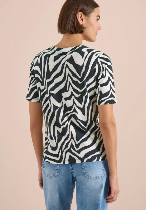 T-Shirt mit Split Neck mit Print palm breeze green Rückenansicht einer Person mit kurzem Haar, die ein zebramuster-T-Shirt und blaue Jeans trägt.