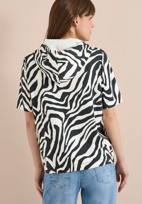 Vrouw van achter in een zebra-print hoodie met korte mouwen en een spijkerbroek.