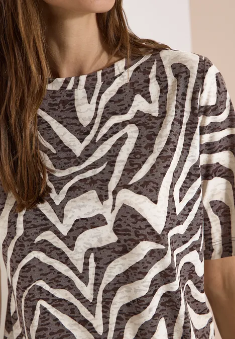 Eine Frau trägt ein kurzärmeliges Shirt mit Zebra-ähnlichem Schwarz-Weiß-Muster.