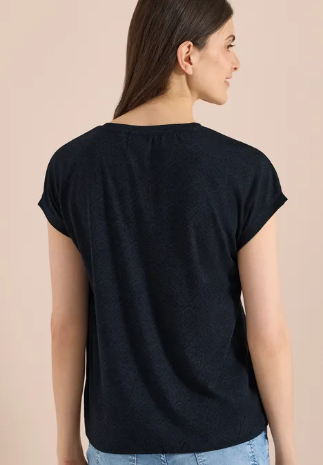 Shirt met burn-out look universal blue Achteraanzicht van een vrouw in een simpel zwart t-shirt tegen een lichte achtergrond.