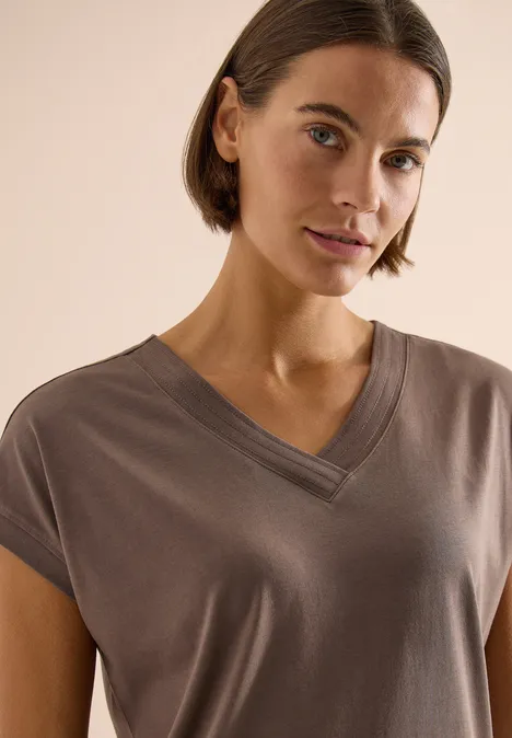 Shirt met korte mouwen en V-hals in effen kleur urban taupe Persoon draagt een taupekleurig kort mouws V-halsshirt.