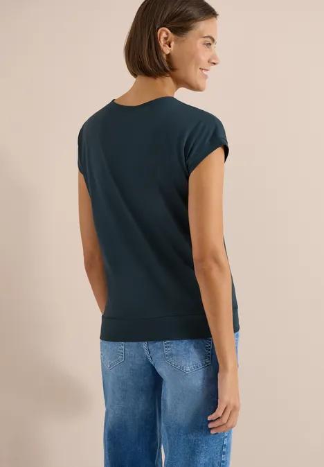 Shirt met korte mouwen en V-hals in effen kleur deep petrol blue Vrouw van achter gezien, draagt een donkerblauw t-shirt met omgeslagen mouwen en een blauwe jeans.