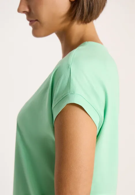 Shirt met korte mouwen en V-hals in effen kleur juicy lime Vrouw in profiel draagt een lichtgroen t-shirt met korte mouwen tegen een neutrale achtergrond.