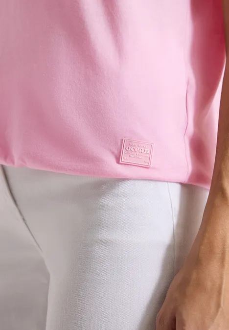 Shirt met boothals en tekstopdruk light blush rose Een roze T-shirt met een klein label in de zoom, gedragen op een witte broek.