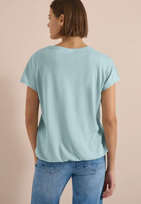 Shirt met V-hals en kanten detail crystal mint Vrouw van achteren met los lichtblauw t-shirt en spijkerbroek.