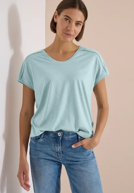 Shirt met V-hals en kanten detail crystal mint Vrouw in turquoise t-shirt en jeans staat ontspannen voor een lichte achtergrond.