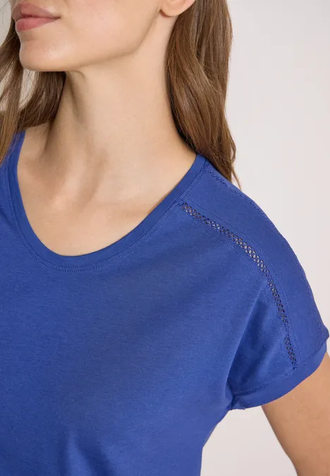 Nahaufnahme einer Frau mit blauem T-Shirt, Oberkörper bis zum Kinn sichtbar.