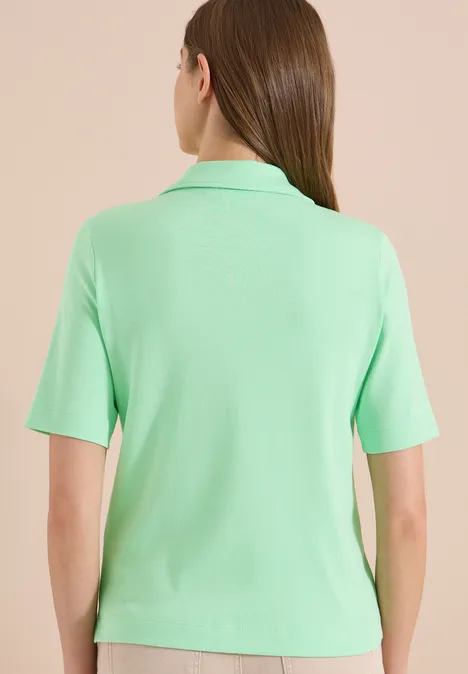 Rugzicht van een persoon in een lichtgroene polo met korte mouwen.