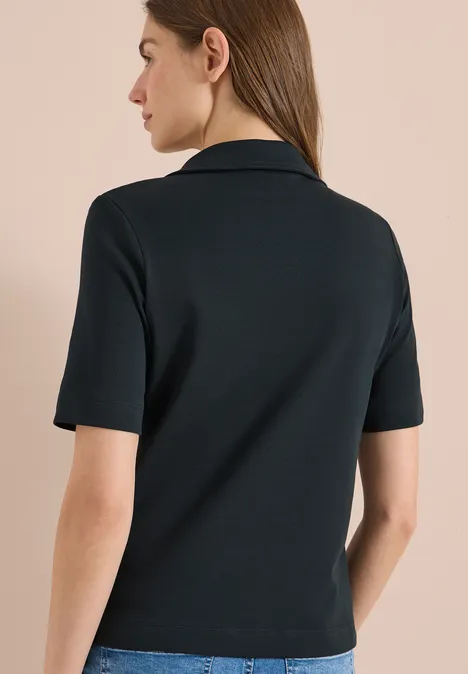 Een persoon van achteren in een zwarte, korte mouwen top tegen een lichte achtergrond.