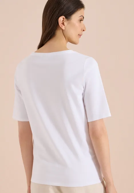 Basic Shirt met boothals White Vrouw van achteren in een wit T-shirt met halflange mouwen voor een effen achtergrond.