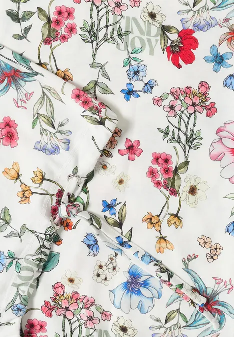 Weißer Stoff mit zartem buntem Blumenmuster in Rot, Blau, Rosa und Gelb.