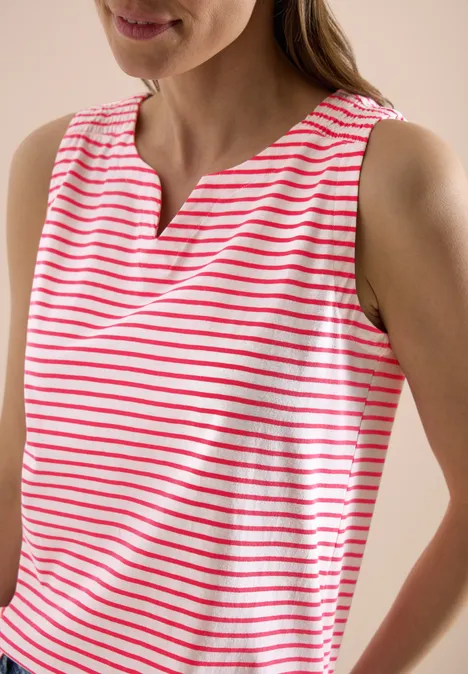 Kobieta w bezrękawniku w czerwono-białe paski.