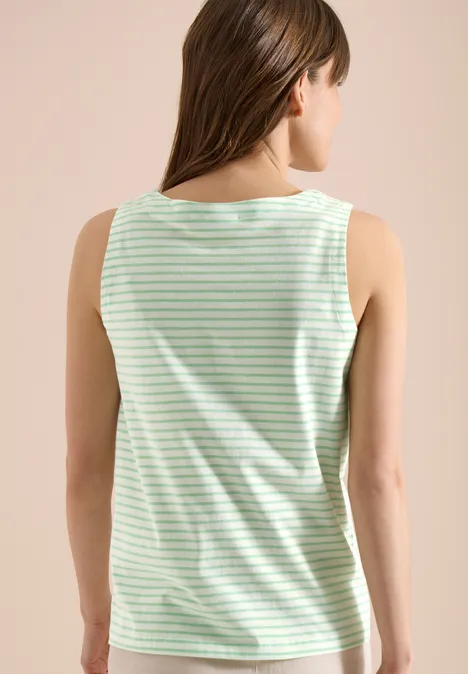 Frau steht mit dem Rücken zur Kamera, trägt ärmelloses, hellgrün-weiß gestreiftes Top.