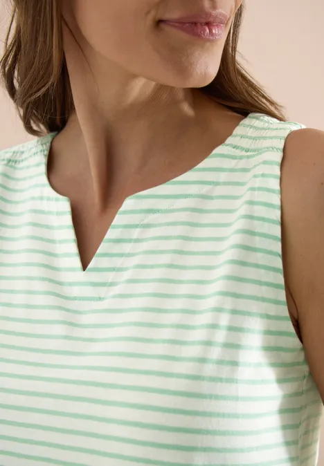 Eine Frau trägt ein ärmelloses, mintgrün-weiß gestreiftes Oberteil mit kleinem V-Ausschnitt.