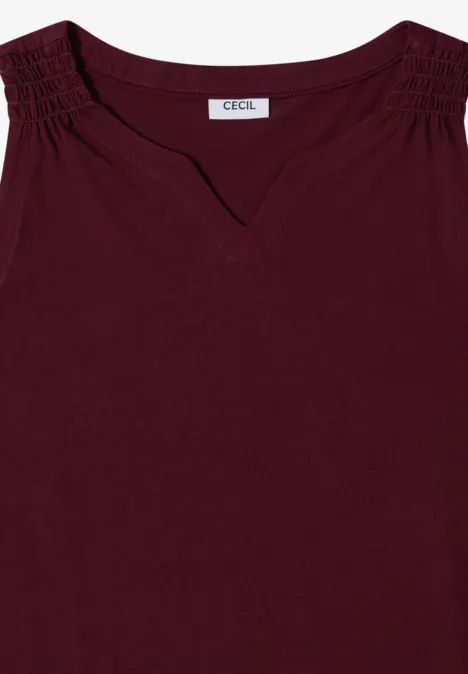 Mouwloos bordeauxrood top met V-hals en gerimpelde schouders.
