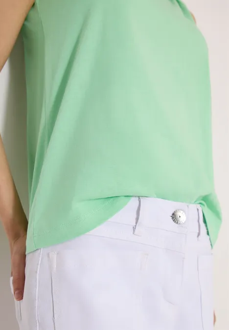 Persoon draagt een groen topje en een witte broek