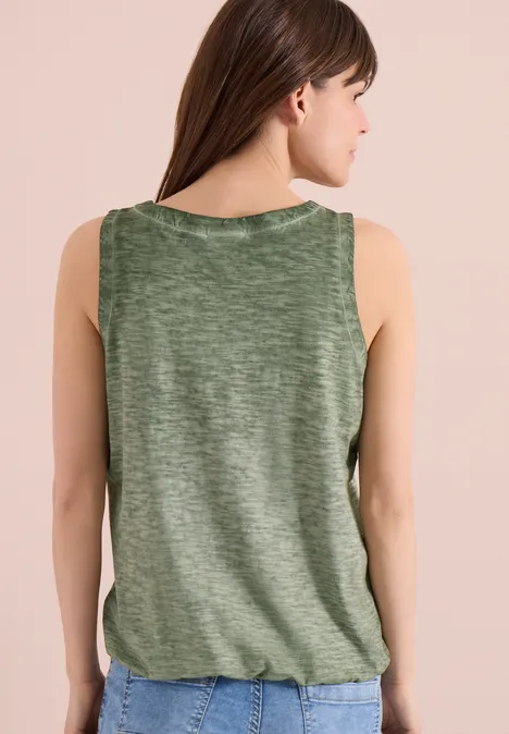 Eine Frau von hinten in einem ärmellosen, grünen Top mit leicht gerafftem Saum.