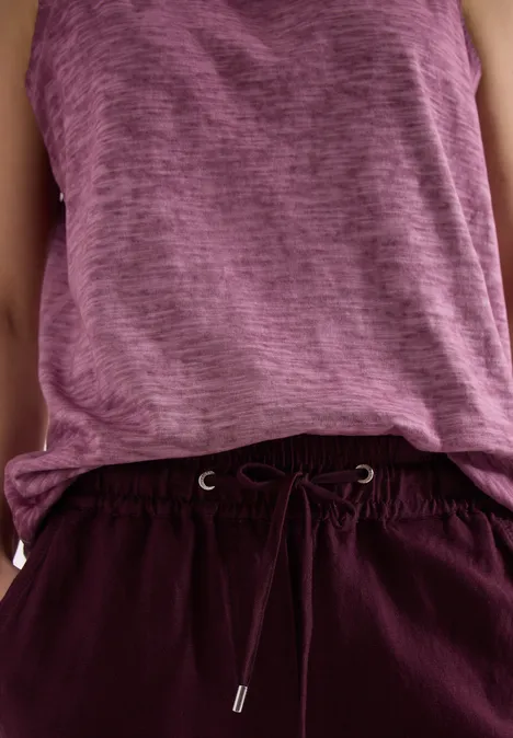 Lässiges Outfit: purpurfarbenes Tanktop und weinrote Hose mit Tunnelzug.