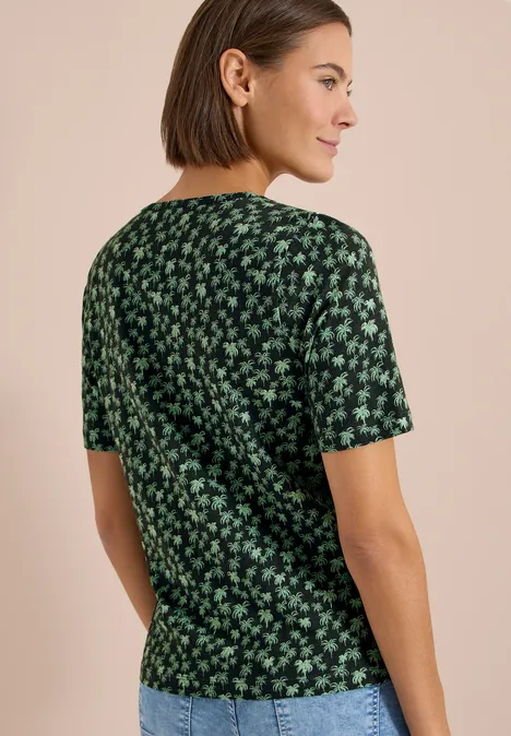 Vrouw van achteren in groen T-shirt met korte mouwen en klein groen bloemenpatroon.